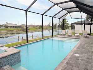 Una piscina con vistas a un estanque y casas al fondo.