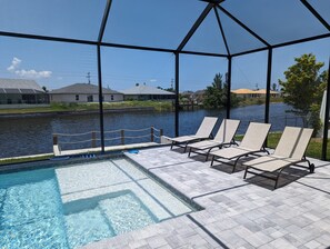 A pool area with lounge chairs and a view of a water body.