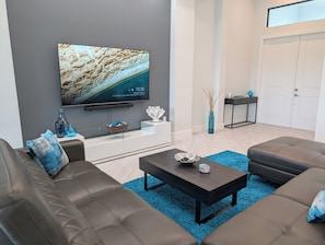 Una sala de estar moderna con televisor de pantalla plana, sofás de cuero, una mesa de centro y objetos decorativos.