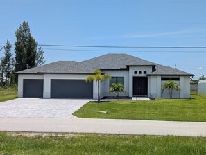 A modern two-story house with a grey roof, a driveway, and a well-maintained lawn.
