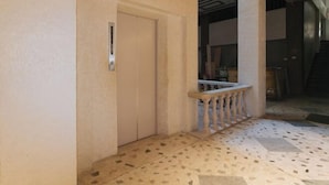 A hallway with a tiled floor, a door, and a staircase in the background.