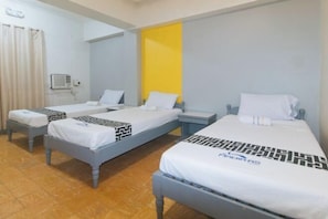 Une chambre d’hôtel avec trois lits, une table de chevet, une commode et une fenêtre avec des rideaux.
