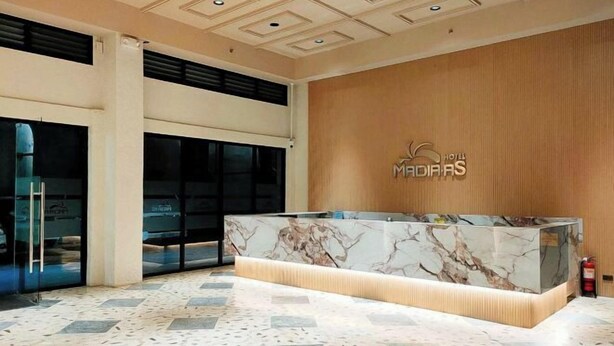 A hotel reception area with a marble counter, large windows, and a wooden wall.