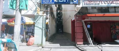 A narrow street with a hotel named "M. DIA. S." and a shop with a red awning.