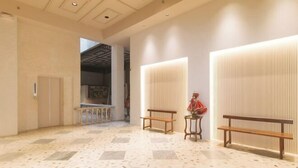 A spacious lobby with a tiled floor, benches, and a statue.