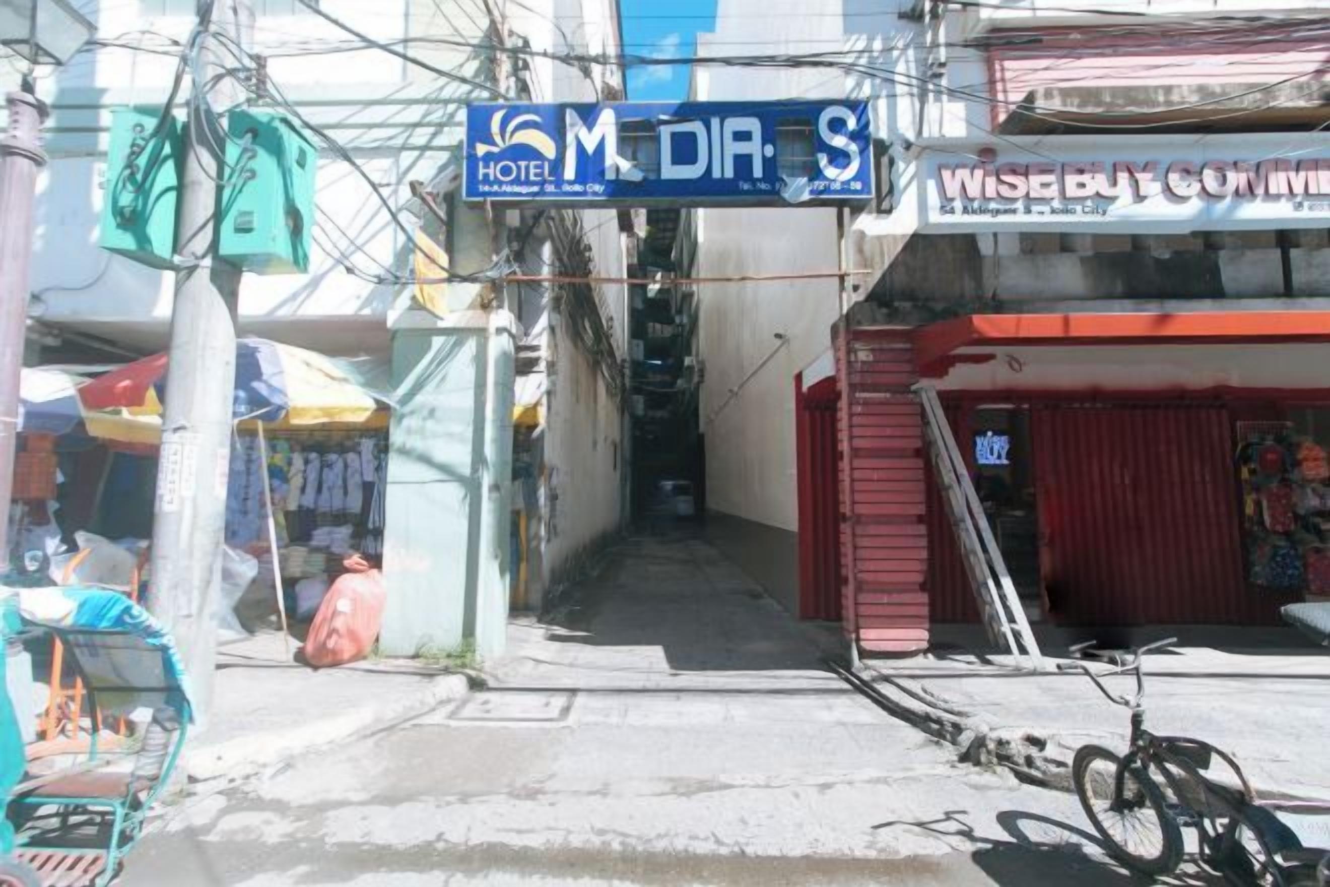 A street view with a hotel named 'M DIA S' and a building with a sign that reads 'WISEBUY COMMERCIAL.'
