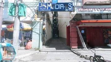 A street view with a hotel named 'M DIA S' and a building with a sign that reads 'WISEBUY COMMERCIAL.'