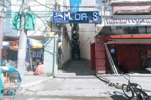 Une vue de rue avec un hôtel appelé « M DIA S » et un bâtiment portant une enseigne indiquant « WISEBUY COMMERCIAL ».