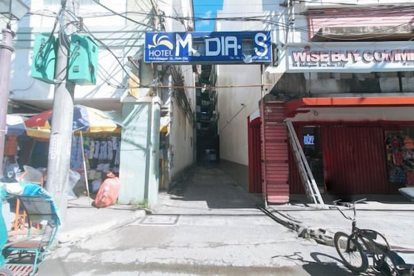 A street view with a hotel named 'M DIA S' and a building with a sign that reads 'WISEBUY COMMERCIAL.' - Hotel Madiaas by RedDoorz (Iloilo City)