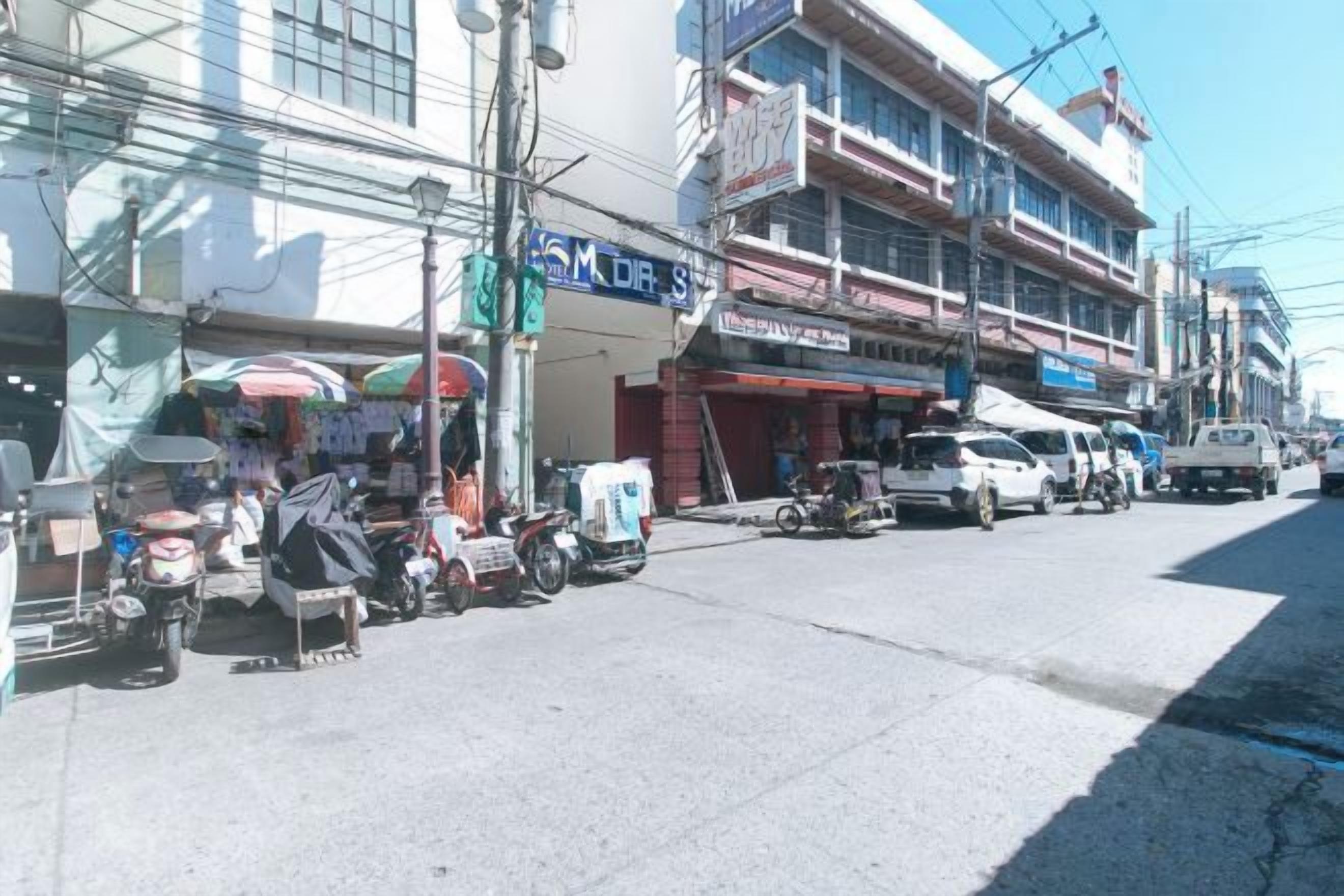 A street with shops and parked vehicles.