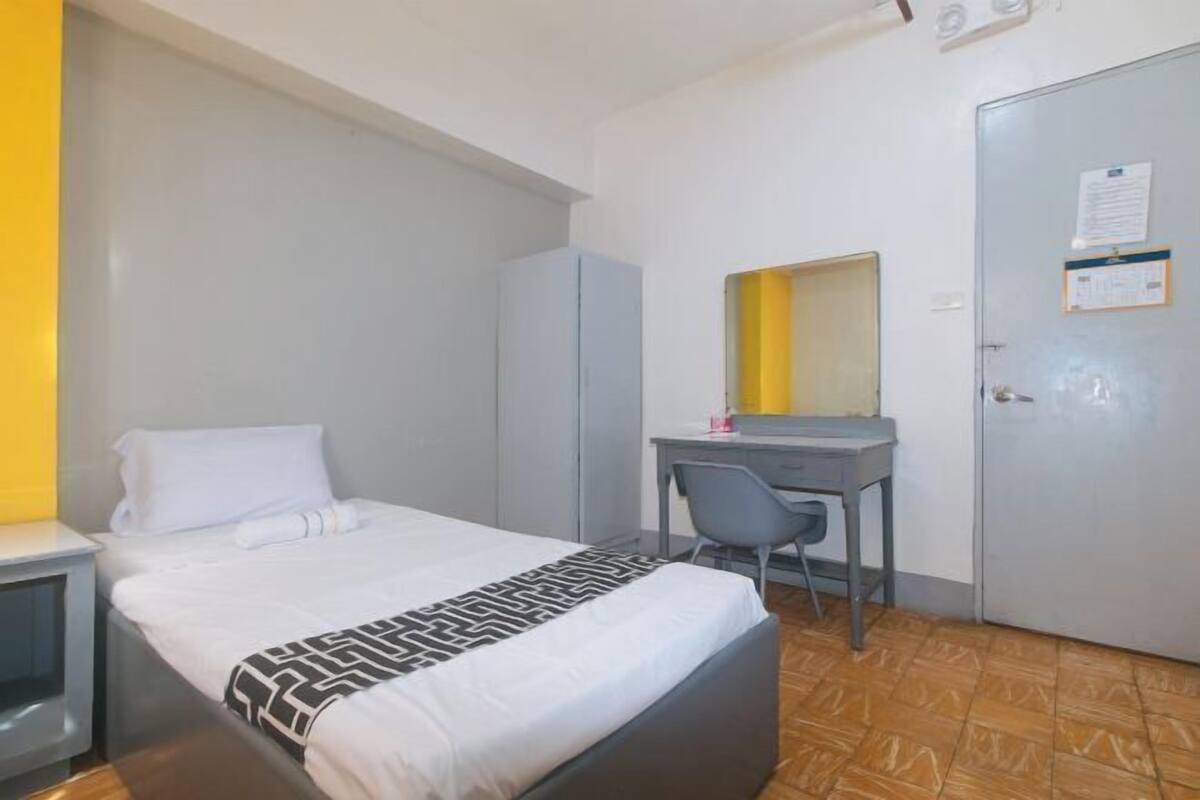 Habitación de hotel con cama, escritorio, silla, armario y puerta con un aviso.