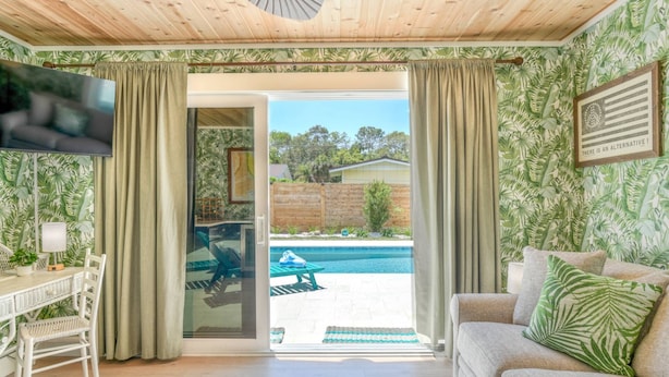 Une pièce avec une piscine, un canapé, une table à manger et un téléviseur.