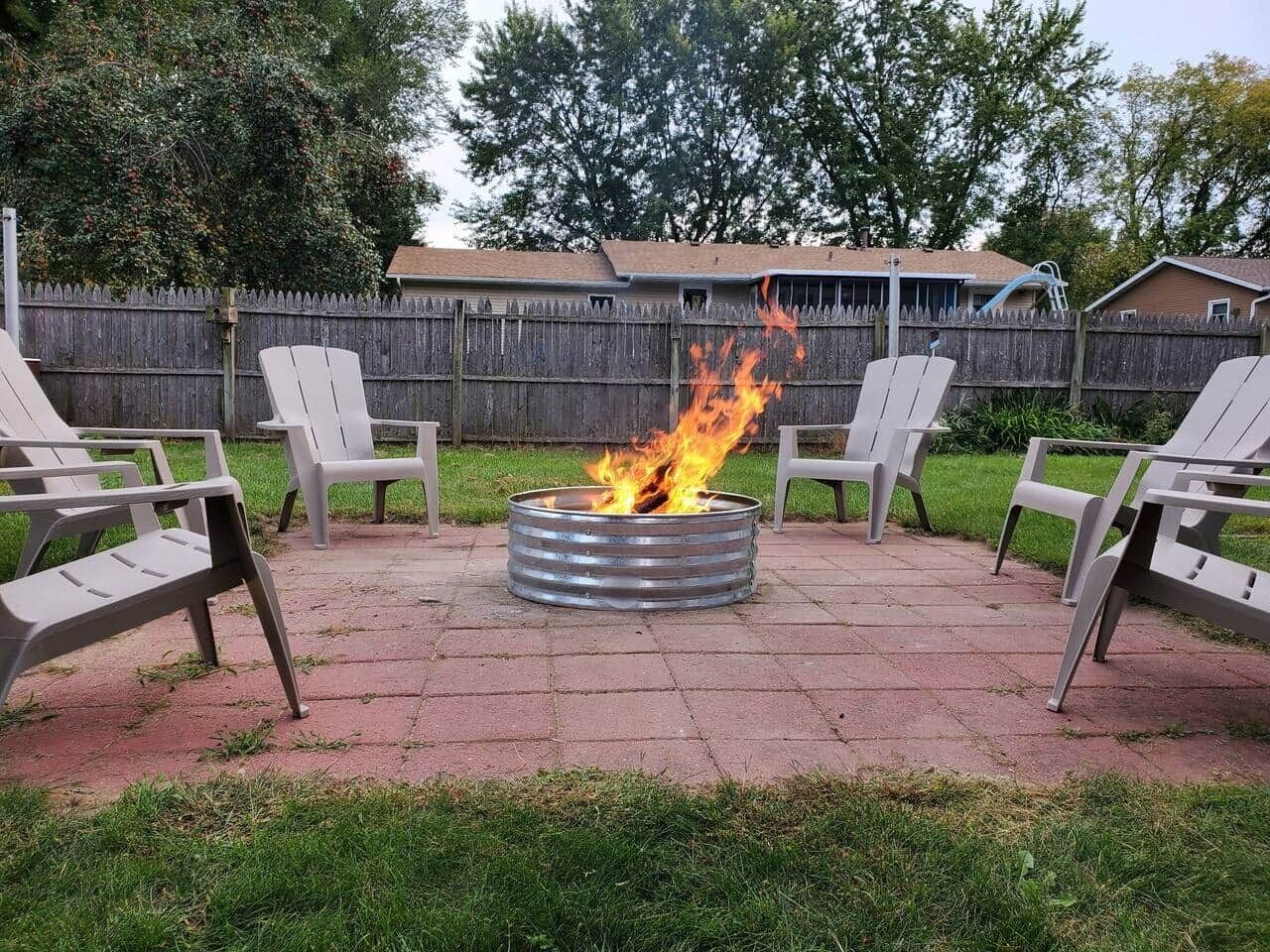 Una chimenea metálica circular con llamas en un patio trasero.