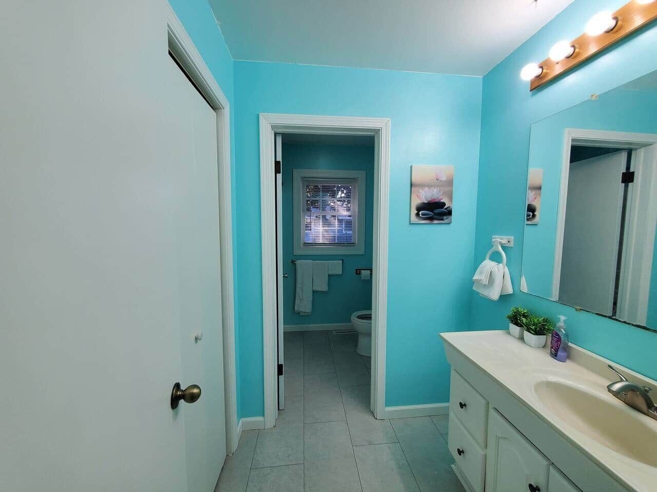 Ein Badezimmer mit blauer Wand, einem weißen Waschbecken und einem Spiegel.
