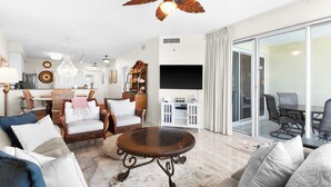 A modern living room with a round coffee table, wicker chairs, and a flat-screen TV. - The Crescent 210 (Miramar Beach)