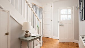 A hallway with a wooden floor, white doors, and a small table with a lamp. - Driftwood (Alnwick)