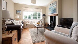 A cozy living room with a fireplace, a sofa, a coffee table, and a television. - Driftwood (Alnwick)