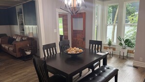 A dining area with a dark wooden table, black upholstered chairs, and a bench. There is a bowl of decorative items on the table.