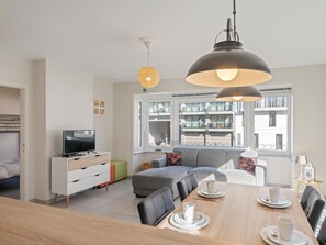 Una sala de estar moderna con sofá, mesa de comedor y televisor.