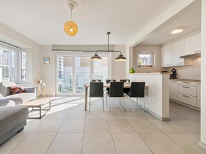 A modern apartment with a dining area, kitchen, and living room.