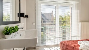 Une salle de bain moderne avec une baignoire, un miroir et une plante en pot.