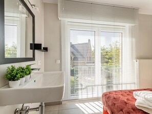 A modern bathroom with a bathtub, a mirror, and a potted plant.