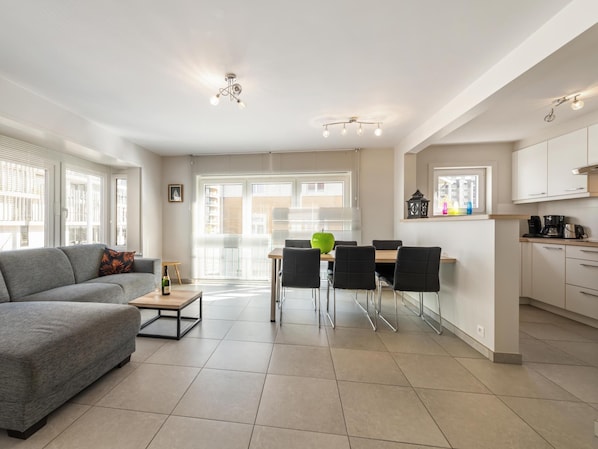 A modern apartment with a dining area, kitchen, and living room.
