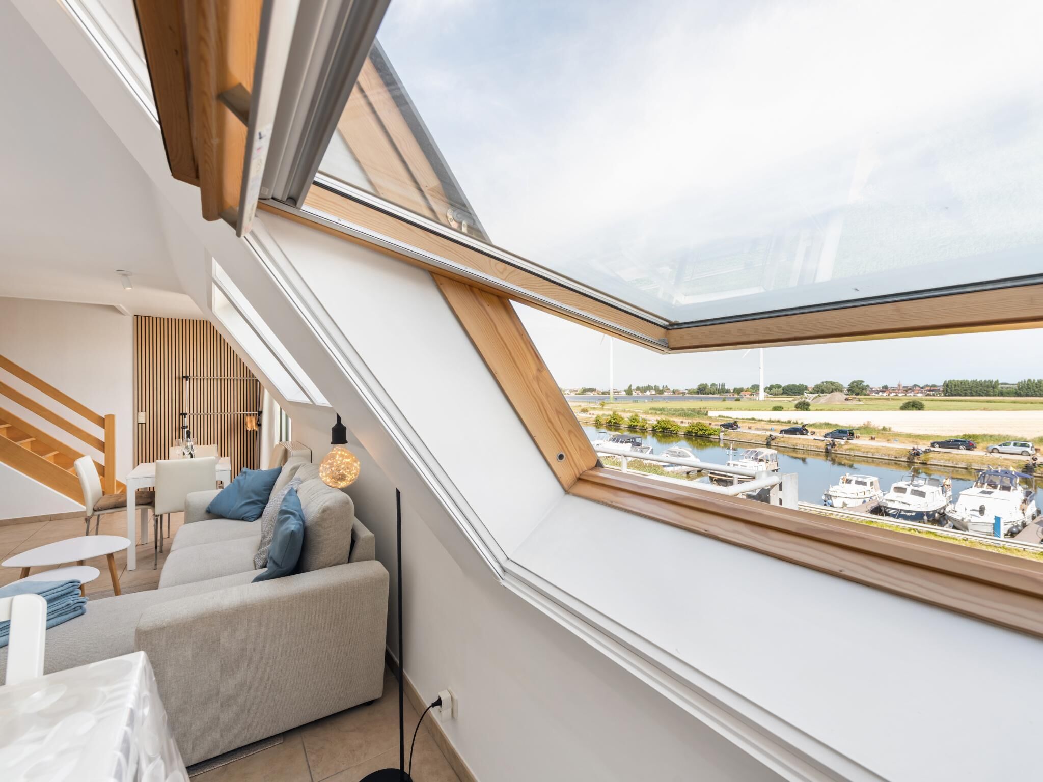 A modern interior with a skylight overlooking a canal and boats.