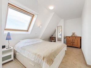 A bedroom with a bed, a nightstand, a lamp, a dresser, and a mirror.