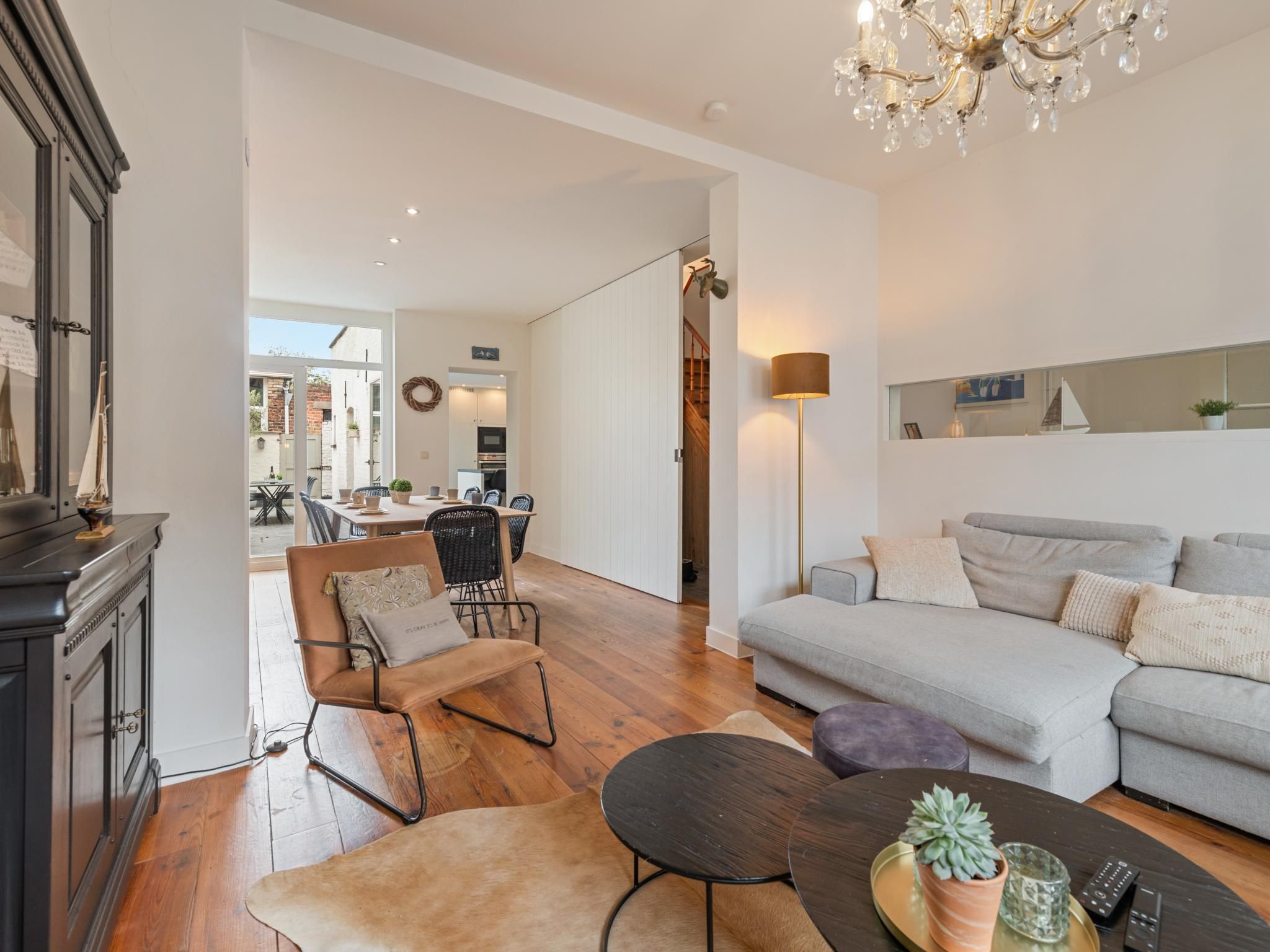 A modern living room with a sofa, a coffee table, and a dining area with chairs and a table.