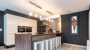 Una cucina moderna con isola centrale, forni integrati e una macchina per il caffè.