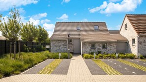 Een woongebouw met een pannendak, bakstenen muren en een verharde oprit met gele gevelaanduiding.