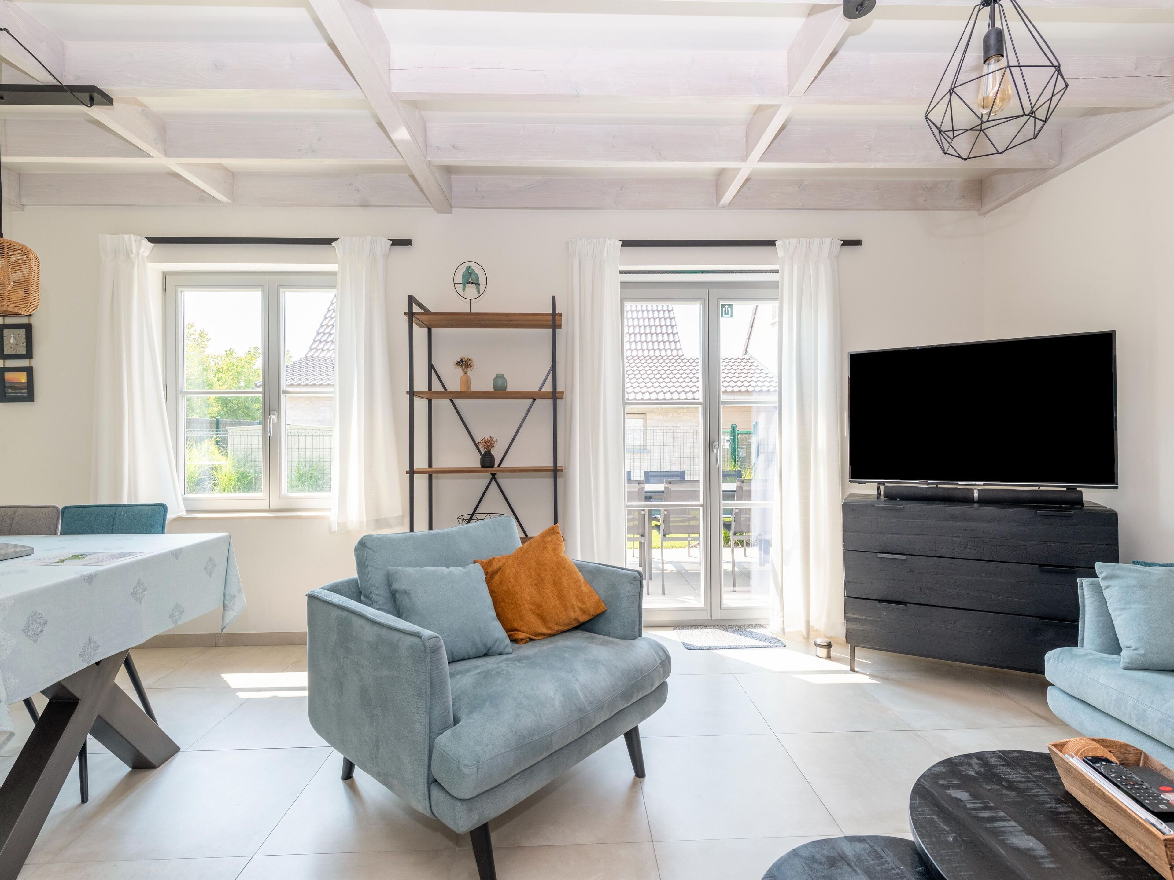 Una sala de estar moderna con un sofá, una mesa de comedor, un televisor y una estantería.