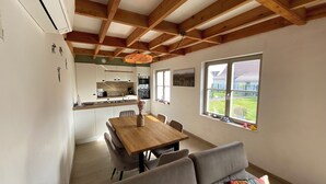 Una cocina moderna con armarios blancos, una mesa de comedor de madera y un amplio ventanal con vistas al exterior.