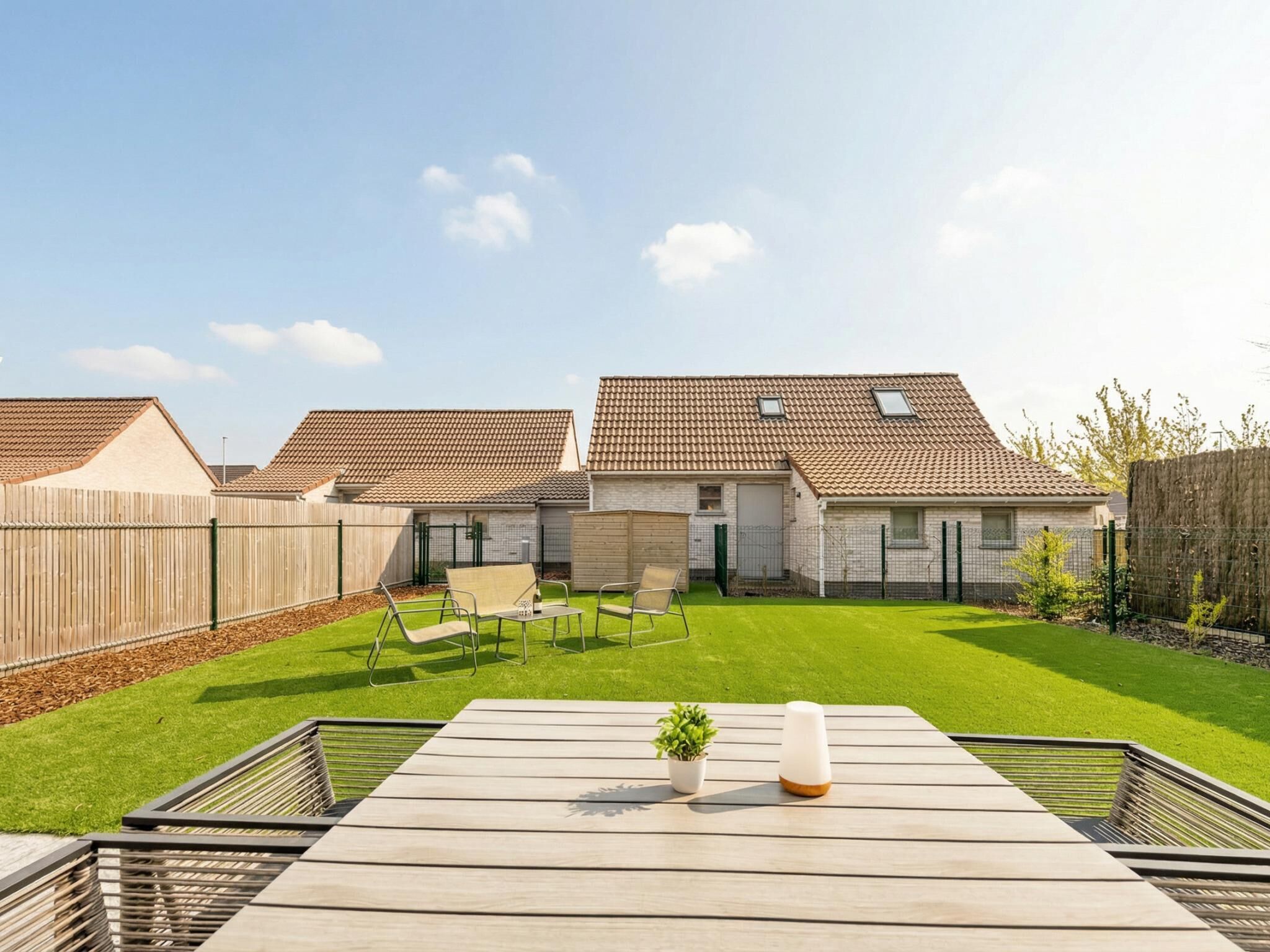 Un quartiere residenziale con due case, un patio in legno e un prato curato.