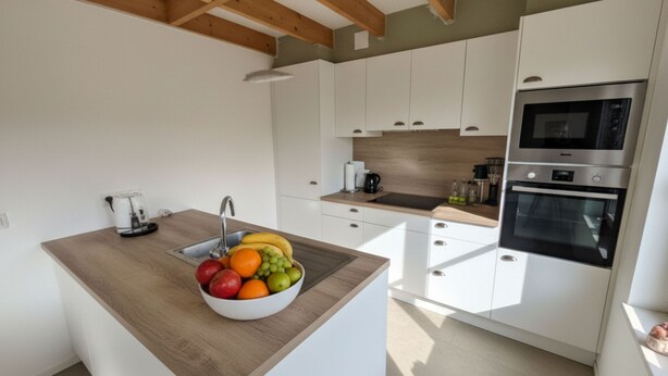 Una cocina moderna con armarios blancos, encimera de madera y un lavamanos empotrado.