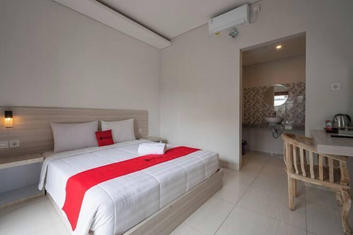 Een hotelkamer met een bed, bureau, stoel, kitchenette en badkamer.