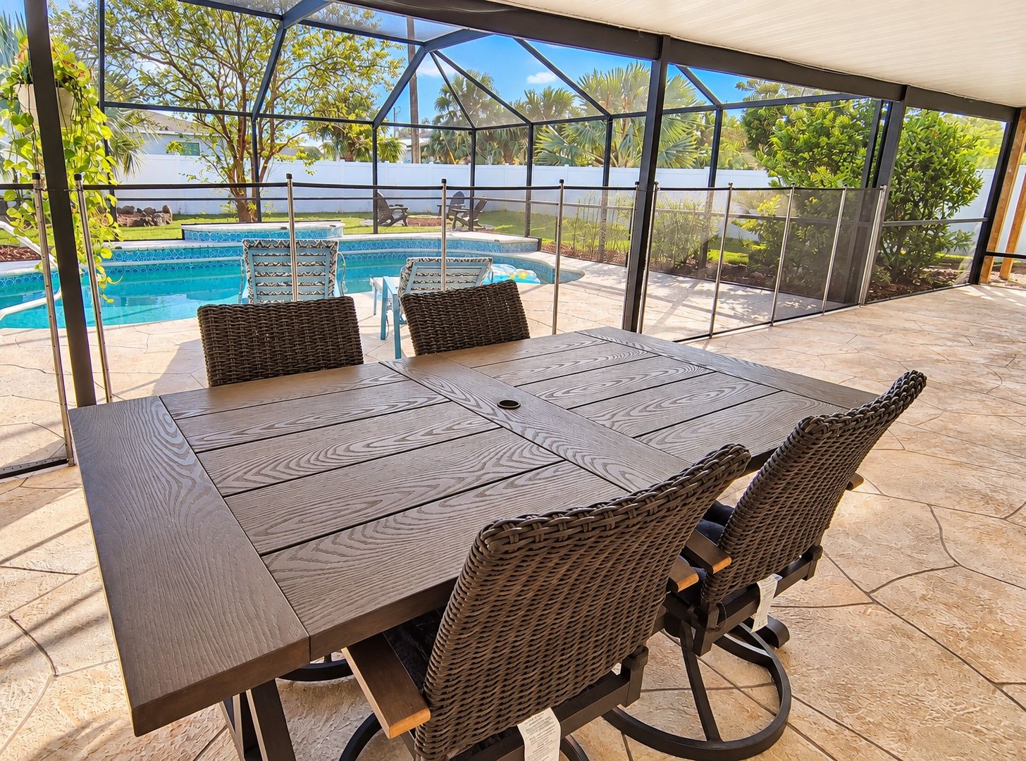 Varanda coberta com mesa e cadeiras, com vista para uma piscina e vegetação.