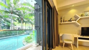 A modern living room with a glass balcony overlooking a pool, a desk with a chair, and a TV. - M city service suite KLCC (Kuala Lumpur)