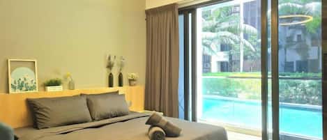 Ein Schlafzimmer mit Bett, Fenster und Blick auf einen Swimmingpool.