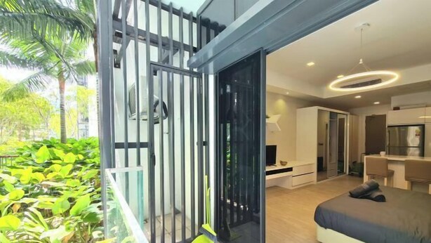 A modern hotel room with a balcony, a bed, a desk, and a view of lush greenery. - M city service suite KLCC (Kuala Lumpur)