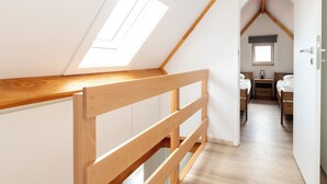 A bedroom with a sloped ceiling, wooden floor, and a skylight. - Contemporary fisher’s house at Westhinder (Koksijde)