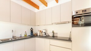 A modern kitchen with white cabinets, a stainless steel sink, a coffee maker, and an oven. - Contemporary fisher’s house at Westhinder (Koksijde)