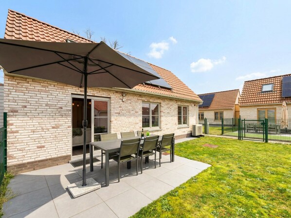A brick house with a patio, a table with chairs, and a large umbrella.