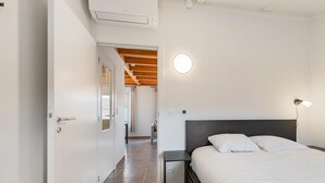 Ein Schlafzimmer mit Bett, Nachttischlampe und Blick auf den Flur.