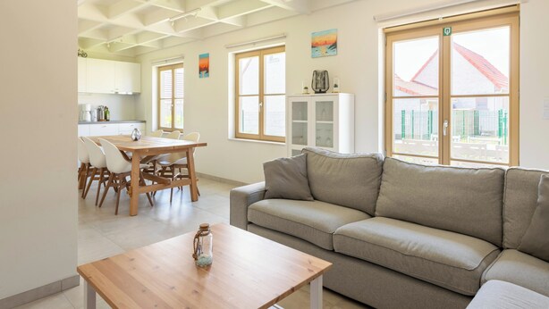 Un salon moderne avec un canapé, une table basse en bois et un coin repas comprenant des chaises et une table.