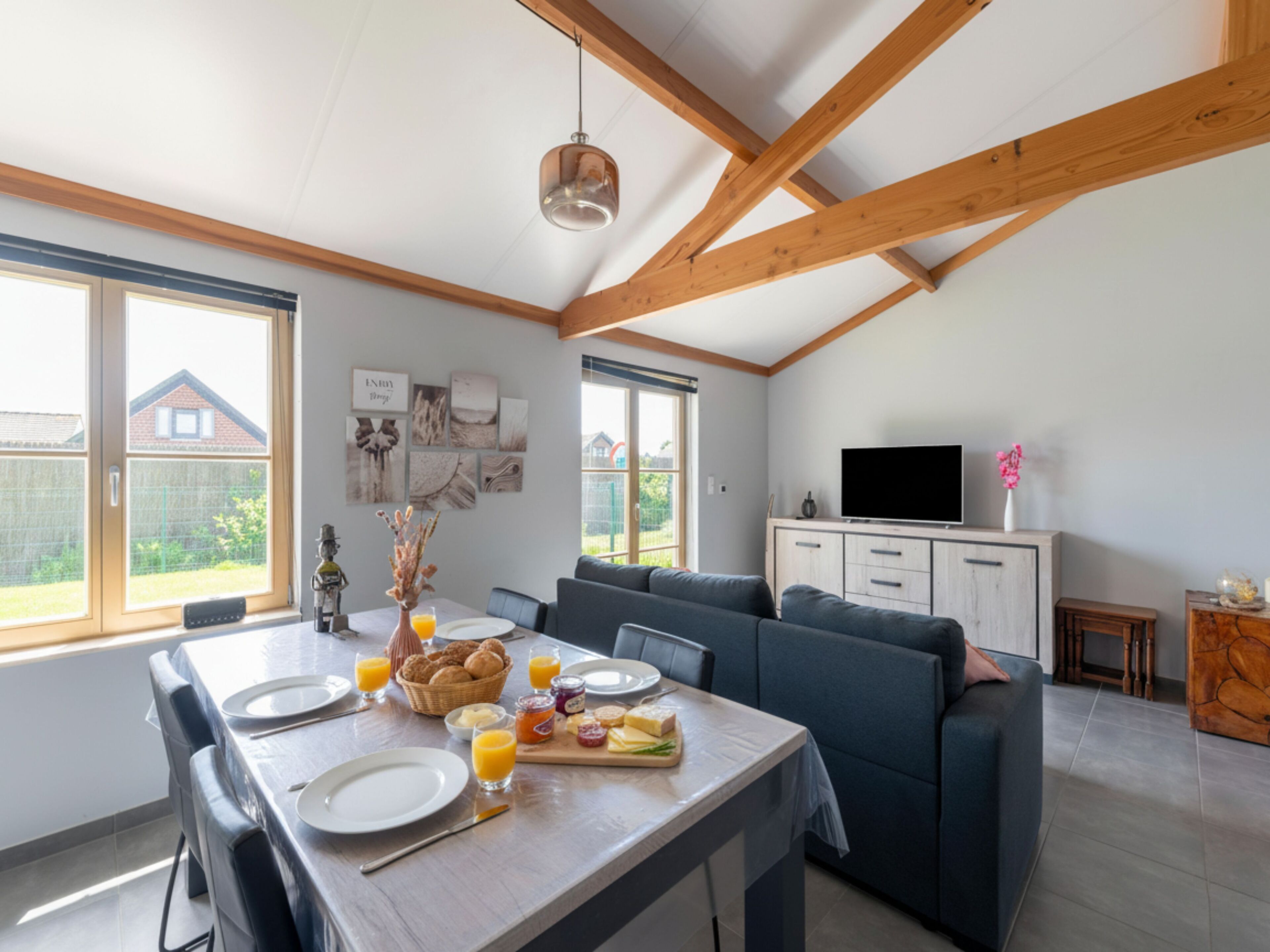 Una cocina moderna con una mesa de comedor dispuesta para el desayuno, un sofá y un televisor en la sala.