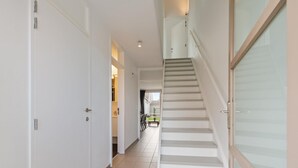 A hallway with a staircase leading to a landing. - Cosy holiday home on the Westhinder domain (Koksijde)
