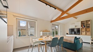 A modern kitchen with a dining area, a sofa, and a TV.