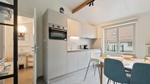 A modern kitchen with a built-in oven, a dining area with a table and chairs, and a window with a view of the outside.